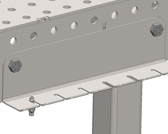 May include: Close-up of a metal workbench with a gray metal plate attached to the side. The plate has a row of slots for holding tools or other items. There is a small black knob on the plate.