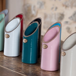 Puede incluir: Siete jarrones de cerámica en diferentes colores, incluyendo turquesa, blanco, rosa y azul. Cada jarrón tiene un borde plateado y un diseño único.