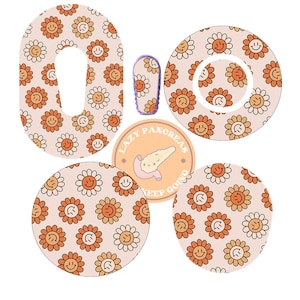 Op de afbeelding: Een set van vijf kleefstickers voor een medisch apparaat. De stickers hebben een lichtroze achtergrond met een herhalend patroon van oranje en witte smiley-bloemen. Eén sticker is rechthoekig met een gat in het midden. De andere vier stickers zijn rond. Eén van de ronde stickers heeft de tekst "Lazy Pancreas Keep Going" met een cartoon-alvleesklier.
