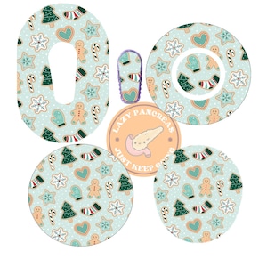 May include: A set of adhesive patches for medical devices featuring a light blue background with a repeating pattern of gingerbread people, Christmas trees, candy canes, hearts, and snowflakes, alongside a circular logo with the text Lazy Pancreas.