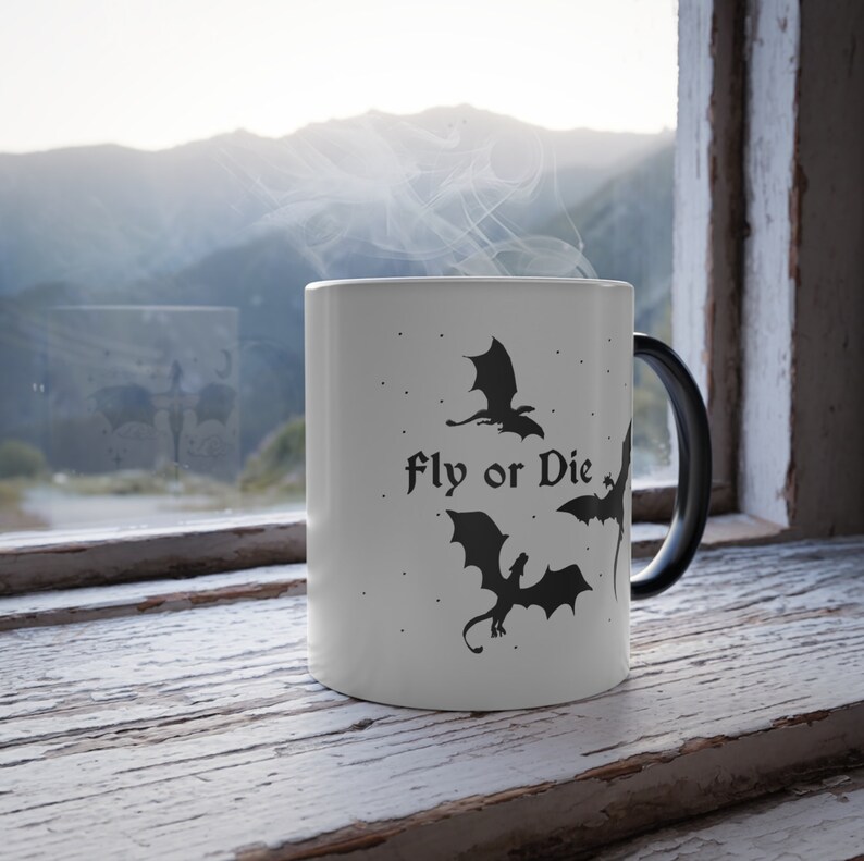 May include: White ceramic mug with a black handle. The mug has a black silhouette of three dragons and the text "Fly or Die" printed on it.