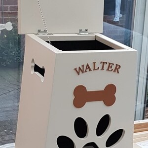 May include: White wooden dog food storage bin with a hinged lid and a paw print cutout. The bin has a brown bone and the name "WALTER" written on the front.