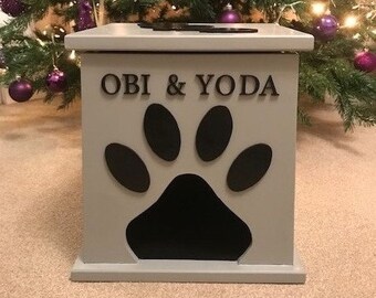 Peut inclure: Une boîte de rangement pour nourriture pour animaux en bois gris avec une découpe en forme de patte et les noms "OBI & YODA" écrits sur le devant.