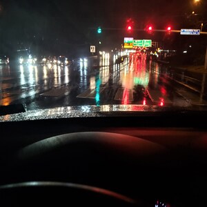 Night view driving down wet highway with bright reflecting colors and signs