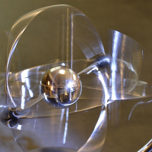 Printable digital download of a kinetic sculpture of metal globe rotating in several axis with blurred motion.