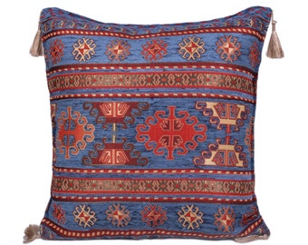 May include: A blue throw pillow with a red, white, and brown geometric pattern. The pillow has tassels on each corner.