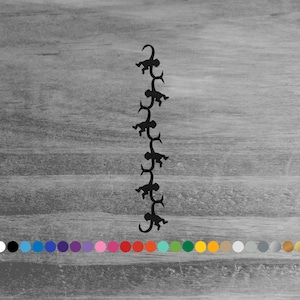 May include: A black silhouette of a chain of monkeys climbing on each other. The monkeys are arranged vertically against a gray wooden background. A color palette of various colors is at the bottom.