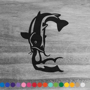 May include: Black metal koi fish silhouette art. The design features a stylized koi fish in a graceful, curved pose. The artwork is set against a gray wooden background, creating a contrast.