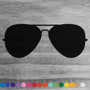 May include: Black aviator sunglasses, a classic eyewear style, are depicted against a gray wood-grain background. The sunglasses feature a double bridge and teardrop-shaped lenses. A selection of color options is shown below the sunglasses.