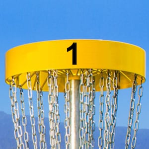 May include: Yellow disc golf basket with a chain link design and the number "1" printed on the top.