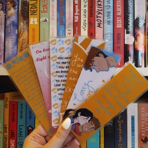 May include: A set of six bookmarks featuring illustrations of couples. The bookmarks are yellow with blue accents and have text on them. The text on one bookmark reads "You have to pretend to get an ending you have to carry on."