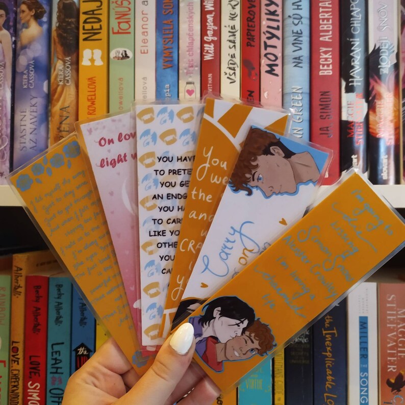 May include: A set of six bookmarks featuring illustrations of couples. The bookmarks are yellow with blue accents and have text on them. The text on one bookmark reads "You have to pretend to get an ending you have to carry on."