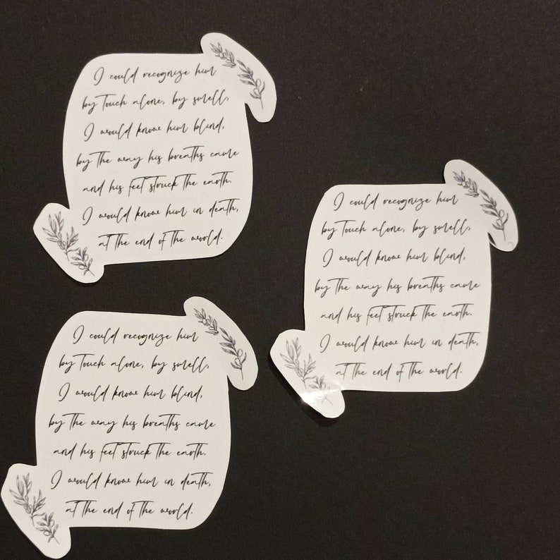 May include: Three white stickers with black text and floral designs. The text on the stickers reads: "I could recognize her by touch alone, by smell. I would know her blind. By the way his breaths wore and his feet struck the earth. I would know her in death, at the end of the world."