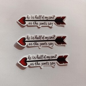 Peut inclure: Trois autocollants blancs avec des c&oelig;urs rouges et des fl&egrave;ches noires. Chaque autocollant porte le texte "he is half of my soul as the poets say" &eacute;crit en cursive noire.