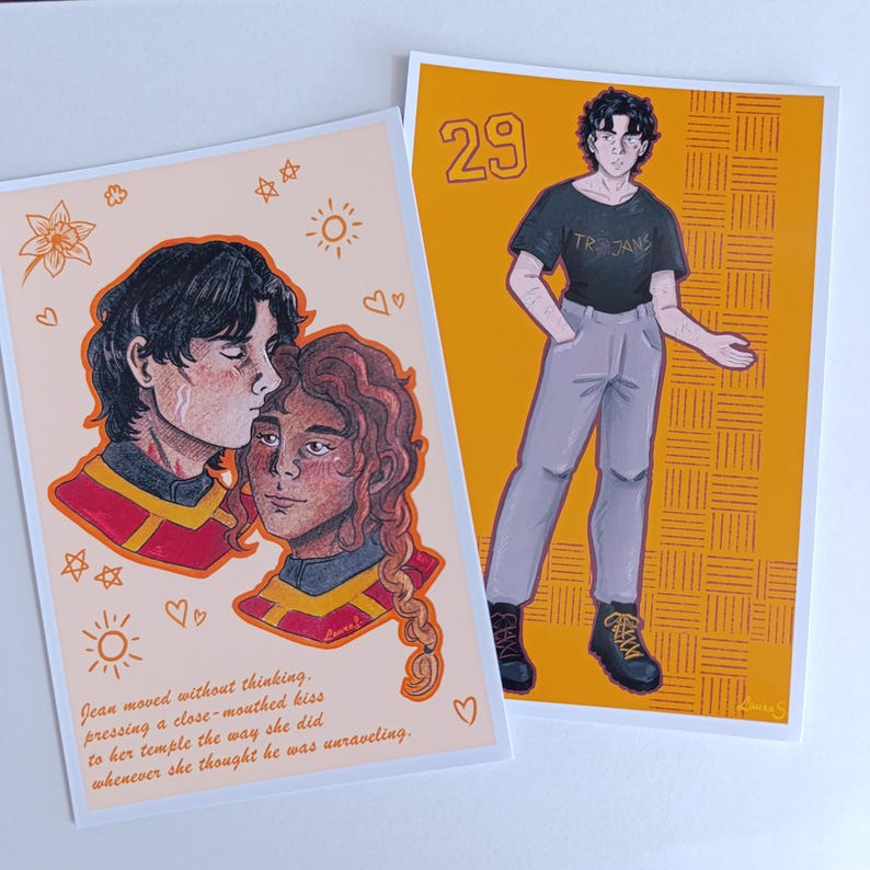 May include: Two art prints. One shows a couple kissing, with text below. The other depicts a person in a black t-shirt with "TROJANS" on it, grey trousers, and black boots. The background is orange with a grid pattern.