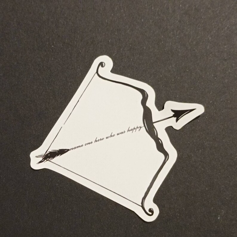 May include: A white sticker with a black and white illustration of a bow and arrow. The sticker has the text "name one hero who was happy" written on it.