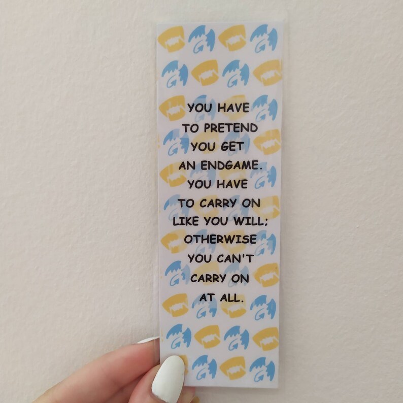 May include: A yellow and blue bookmark with a repeating pattern of wings. The bookmark has a quote that reads: "You have to pretend you get an endgame. You have to carry on like you will; otherwise you can't carry on at all."
