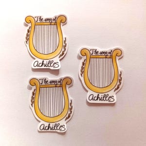 Peut inclure: Trois autocollants dor&eacute;s et blancs avec un dessin de lyre et le texte "The song of Achilles".