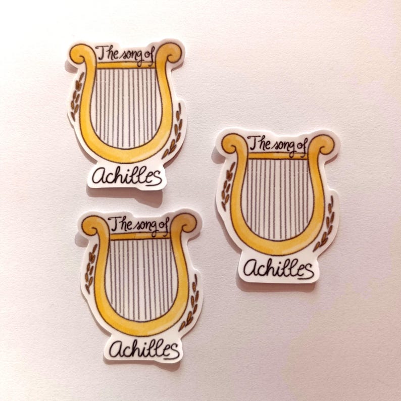 Peut inclure: Trois autocollants dor&eacute;s et blancs avec un dessin de lyre et le texte "The song of Achilles".