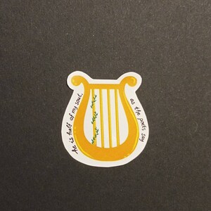 May include: A yellow lyre with a green vine growing up the side. The text "He is half of my soul, as the poets say" is written around the lyre.