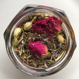 May include: A glass jar filled with dried herbs, rose petals, and lavender buds. The jar is clear and has a lid.