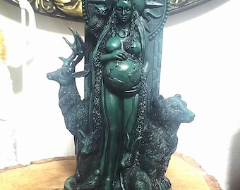 May include: A dark green statue of a woman holding a globe, surrounded by animals including a deer, bear, and rabbit. The statue has a sun-like halo and is on a round base with etched symbols. The statue is approximately 10 inches tall.