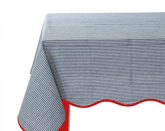 May include: A blue and white striped tablecloth with a scalloped edge and a red trim. The tablecloth is draped over a red table.