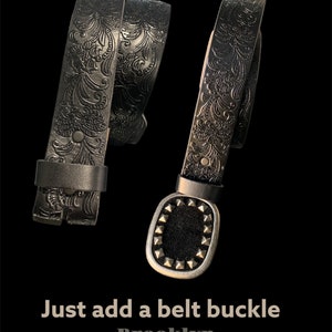 K&ouml;nnte beinhalten: Schwarzer Lederg&uuml;rtel mit einem gepr&auml;gten Blumenmuster. Der G&uuml;rtel ist in der H&auml;lfte gefaltet und enth&auml;lt eine silberfarbene Schnalle mit einem Nietendesign. Der Text "Just add a belt buckle" und "Brooklyn Buckles" ist unterhalb des G&uuml;rtels sichtbar.