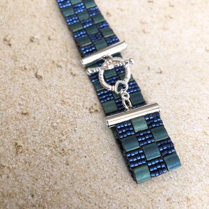May include: A blue and green beaded bracelet with a silver toggle clasp.