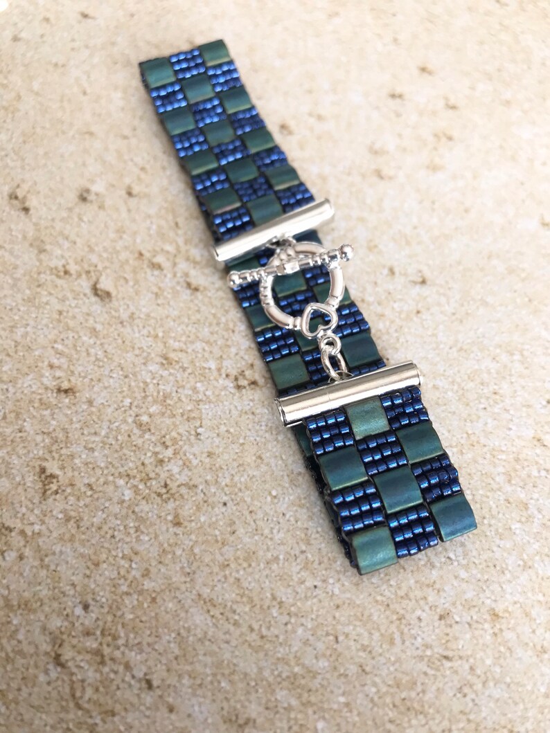 May include: A blue and green beaded bracelet with a silver toggle clasp.