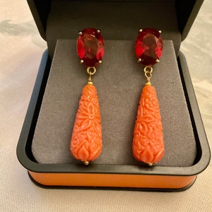 Peut inclure: Une paire de boucles d'oreilles pendantes avec des gouttes de pierres précieuses rouges et des pendentifs en corail sculptés en forme de larme.