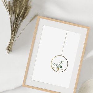 May include: A framed print of a minimalist illustration of a hanging plant in a gold circle. The plant has green leaves and is suspended from a thin string.