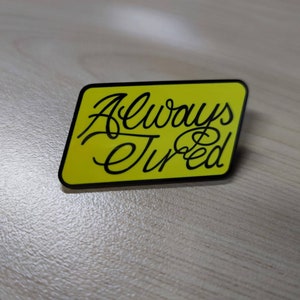 Puede incluir: Una pegatina amarilla con texto negro que dice "Siempre cansado".