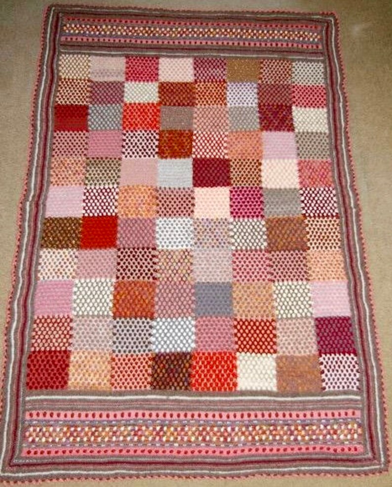 May include: A handmade, rectangular crochet blanket featuring a patchwork design. The blanket showcases a variety of colors, including red, pink, brown, and white, arranged in a grid pattern. The border is a darker shade with a decorative trim.