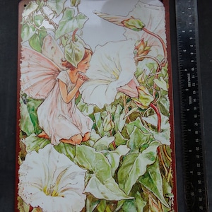 May include: A vintage-style metal sign featuring a fairy with pink wings sitting on a white bindweed flower. The sign has a red border and the text "The White Bindweed Fairy" at the bottom.