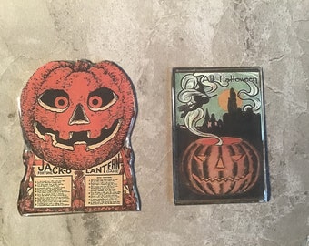 Könnte beinhalten: Zwei Vintage-Dekorationen zum Thema Halloween. Eines ist ein Jack-O-Lantern-Wahrsagespiel mit einem lächelnden Kürbisgesicht. Das andere ist ein rechteckiges Bild mit einer Hexe, die über einem Kürbis mit dem Text "All Halloween" fliegt.