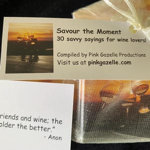 Op de afbeelding: Een rechthoekige witte kaart met een zonsondergangafbeelding van wijnglazen en de tekst 'Savour the Moment 30 savvy sayings for wine lovers! Compiled by Pink Gazelle Productions Visit us at pinkgazelle.com' naast een kaart met de tekst 'Friends and wine; the older the better.' - Anon.