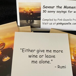 Op de afbeelding: Een set vierkante kaarten met citaten over wijn. E&eacute;n kaart toont de tekst "Either give me more wine or leave me alone." - Rumi. De koptekst op de verpakking luidt "Savour the Moment 30 savvy sayings for wine lovers! Compiled by Pink Gazelle Productions."