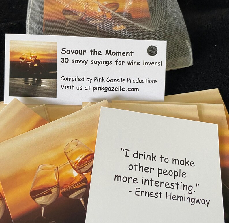Op de afbeelding: Een set witte kaarten getiteld Savour the Moment 30 savvy sayings for wine lovers samengesteld door Pink Gazelle Productions. Elke kaart bevat een afbeelding van wijnglazen bij zonsondergang en een citaat, waaronder een van Ernest Hemingway.