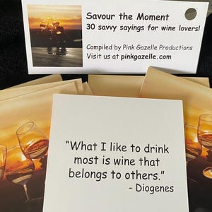 Op de afbeelding: Een set vierkante kaarten met citaten over wijn. De bovenste kaart toont de tekst: "Savour the Moment, 30 savvy sayings for wine lovers! Compiled by Pink Gazelle Productions. Visit us at pinkgazelle.com." Een andere kaart toont het citaat: "What I like to drink most is wine that belongs to others." - Diogenes, tegen een achtergrond van een zonsondergang met wijnglazen.