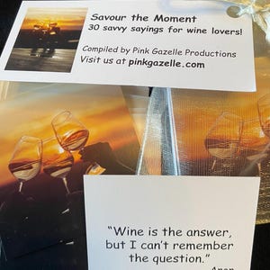 Op de afbeelding: Een set kaarten getiteld Savour the Moment 30 savvy sayings for wine lovers door Pink Gazelle Productions. De kaarten bevatten afbeeldingen van wijnglazen bij zonsondergang en citaten zoals Wine is the answer, but I can't remember the question. Anon.
