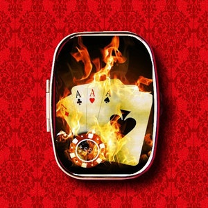 May include: Four aces playing cards are engulfed in flames, with a poker chip in the centre. The cards and chip are inside a round, silver-rimmed container.