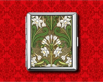 May include: A silver cigarette case with a floral design. The case features an Art Nouveau style illustration of white flowers, green leaves, and brown stems. The case is set against a red patterned background. The design is reminiscent of the Art Nouveau period.