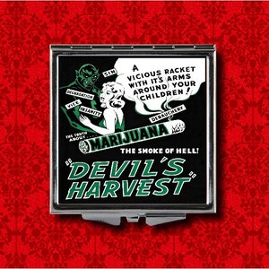 May include: A black and white compact mirror with a graphic of a devil and a woman holding a cigarette. The text reads "The Truth About Marijuana, The Smoke of Hell! Devil's Harvest".