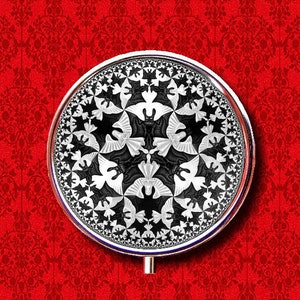 May include: A silver-colored round compact mirror with a black and white optical illusion design of bats and birds. The mirror is on a red background with a floral pattern.