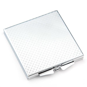 May include: A silver compact mirror with a textured surface and a hinged lid.