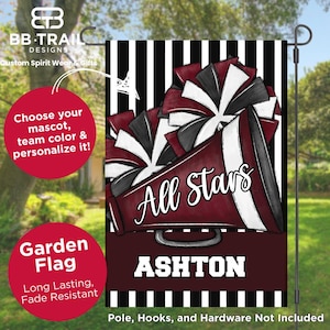 May include: A maroon and white garden flag with a cheerleader theme. The flag features a megaphone with "All Stars" written on it, along with the name "Ashton". The background has black and white stripes. The flag is designed for outdoor use.
