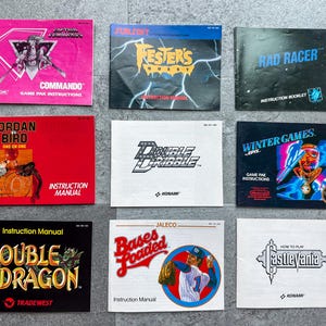May include: Nine vintage video game instruction manuals are displayed. Titles include "Commando," "Fester's Quest," "Rad Racer," "Jordan Bird," "Double Dribble," "Winter Games," "Double Dragon," "Bases Loaded," and "Castlevania."