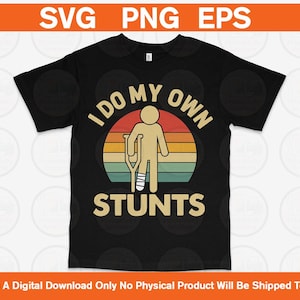 Op de afbeelding: Zwart T-shirt met een grafische afbeelding van een stokfiguur met een been in het gips en een kruk, tegen een zonsondergang. De tekst luidt "I DO MY OWN STUNTS" in een vetgedrukte lettertype.