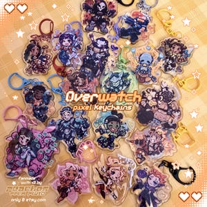 May include: A selection of Overwatch pixel keychains, each with a different character design. The keychains are transparent with vibrant colours and key rings. The text "Overwatch pixel Keychains" is displayed.